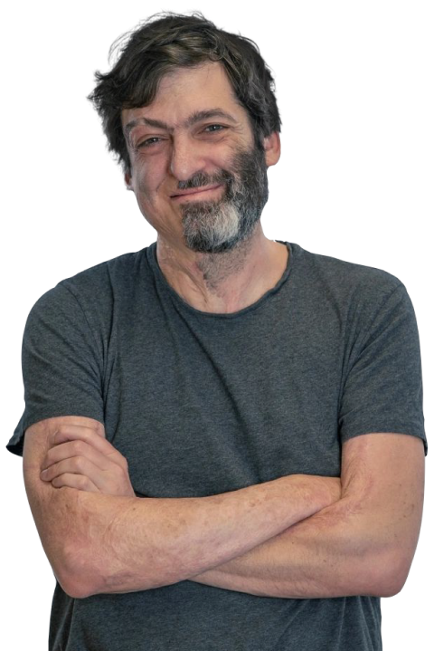 A photo of Dan Ariely smiling with crossed hands in front of him